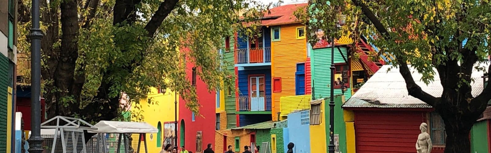 A line of bright, multicolored houses sit behind trees. 